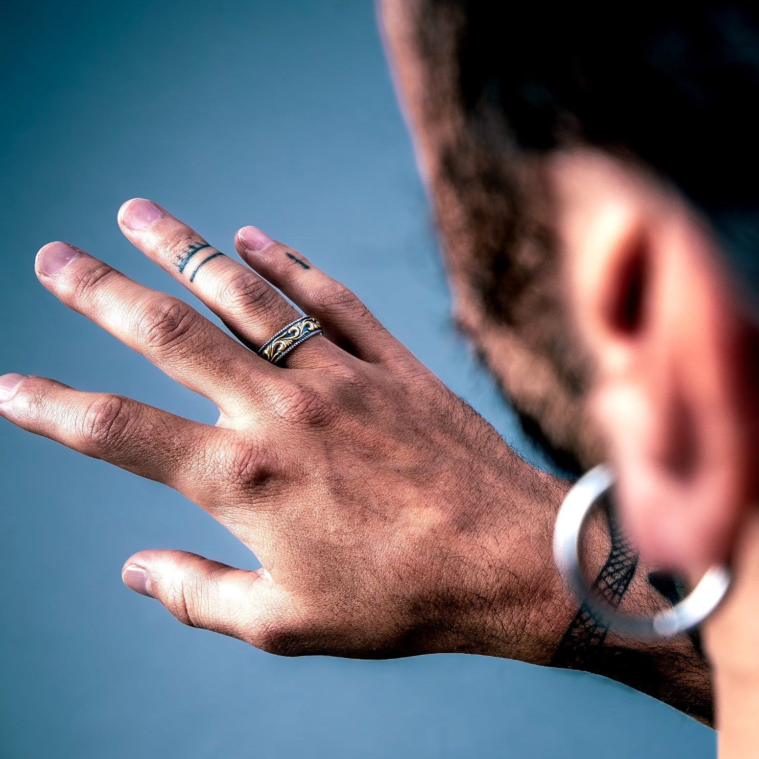 [full] Person with tattoos wearing an statement sterling silver ring