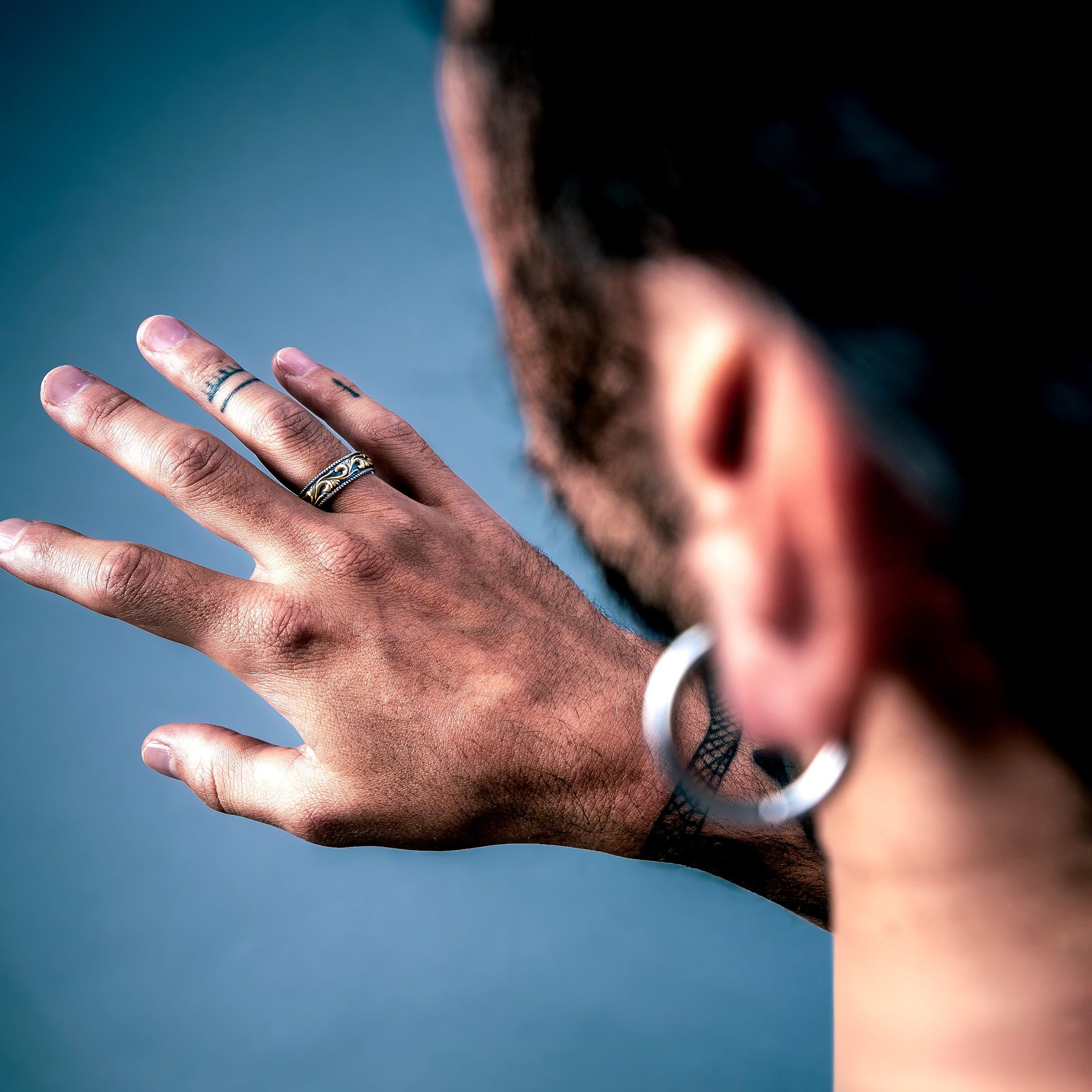 [full] Person with tattoos wearing an statement sterling silver ring