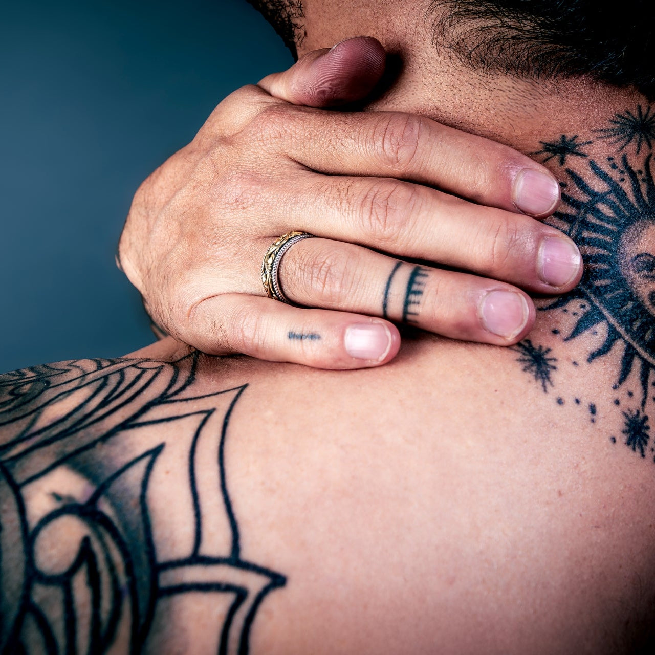 [full] Person with tattoos on shoulder and neck wearing an statement sterling silver ring