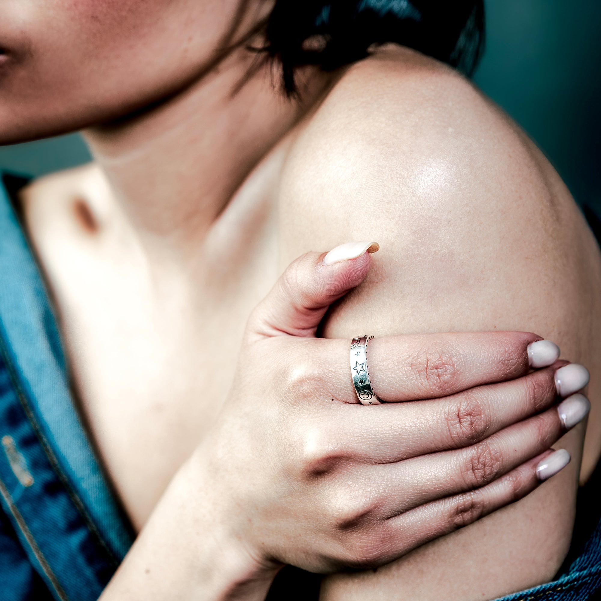 [full] Woman with a sterling silver ring on her finger touching her shoulder.