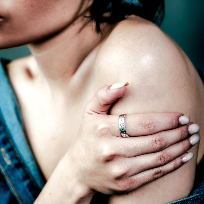 [full] Woman with a sterling silver ring on her finger touching her shoulder.