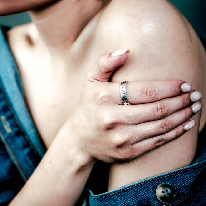 [full] Woman with a sterling silver ring on her finger touching her shoulder.
