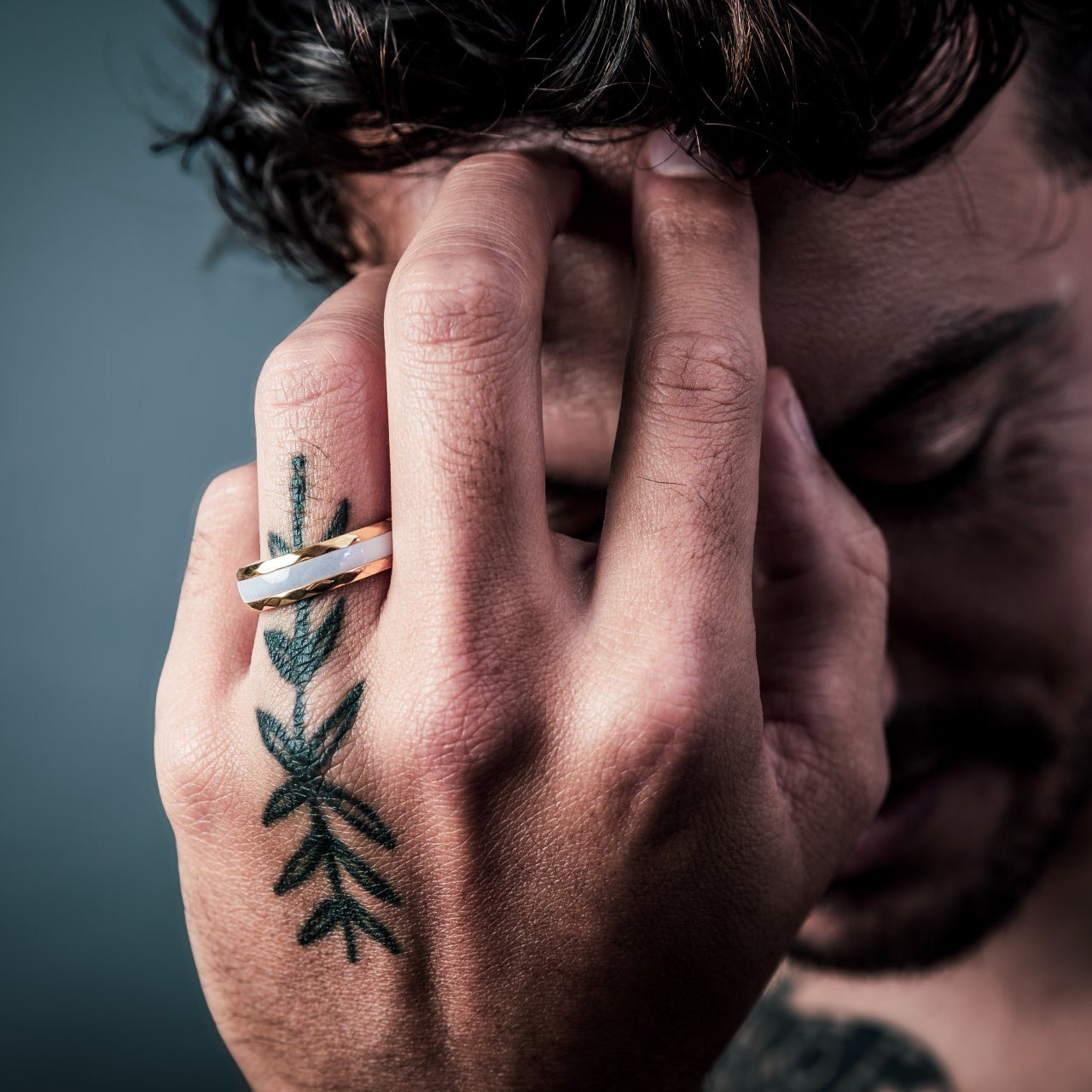 [full] Man with tattooed hand holding head wearing white ceramic ring