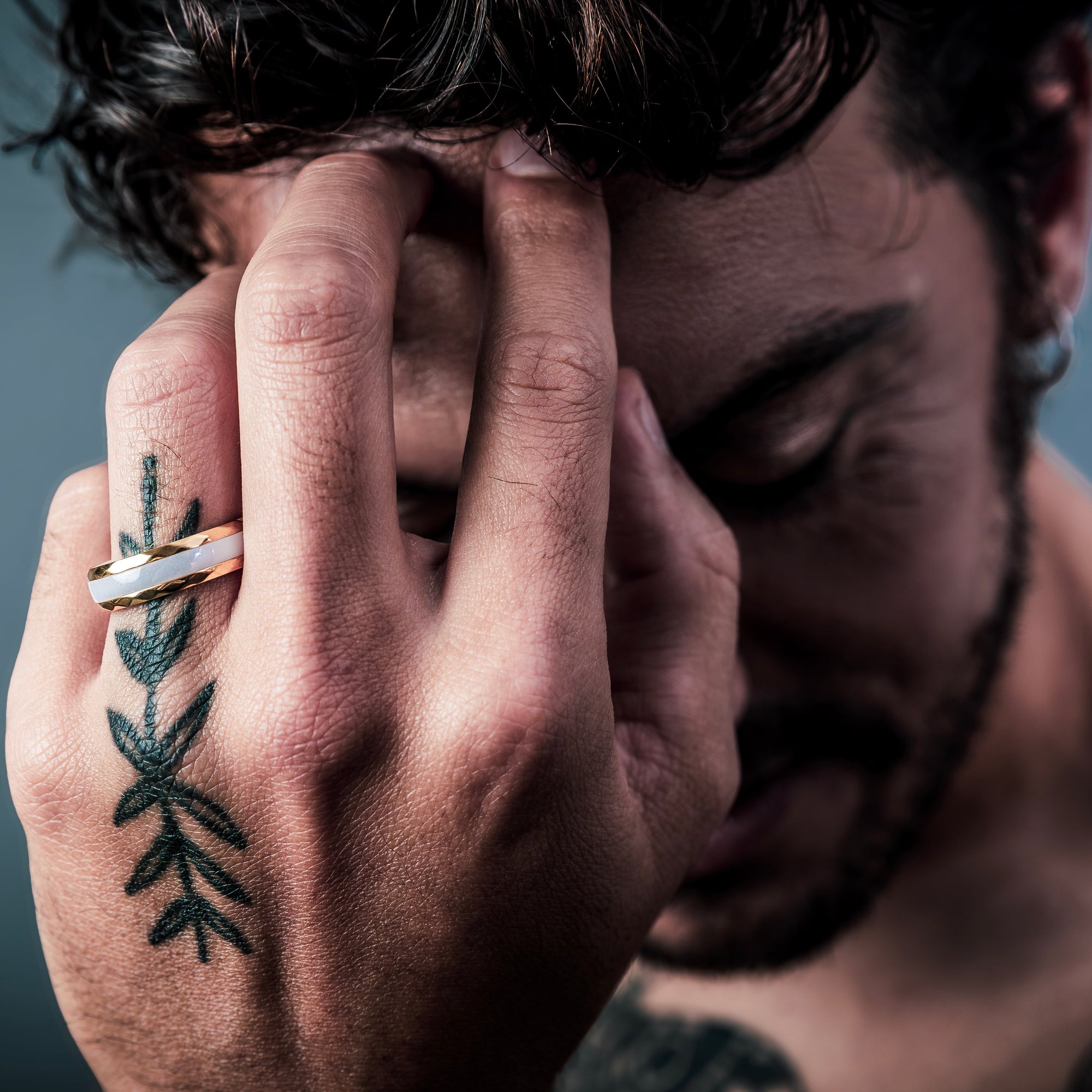 [full] Man with tattooed hand holding head wearing white ceramic ring
