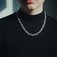 [full] Person wearing a silver chain necklace against a dark background