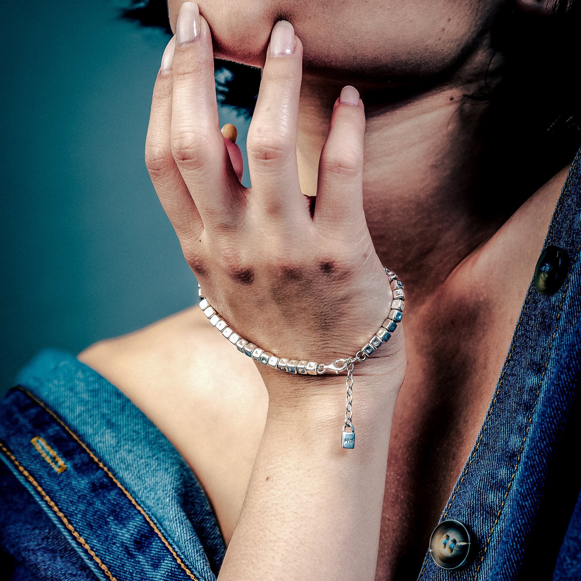 [full] Woman with dark hair and denim jacket wearing a sterling silver cube beads bracelet with matte finish and adjustable closure.