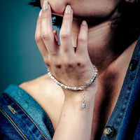 [full] Woman with dark hair and denim jacket wearing a sterling silver cube beads bracelet with matte finish and adjustable closure.