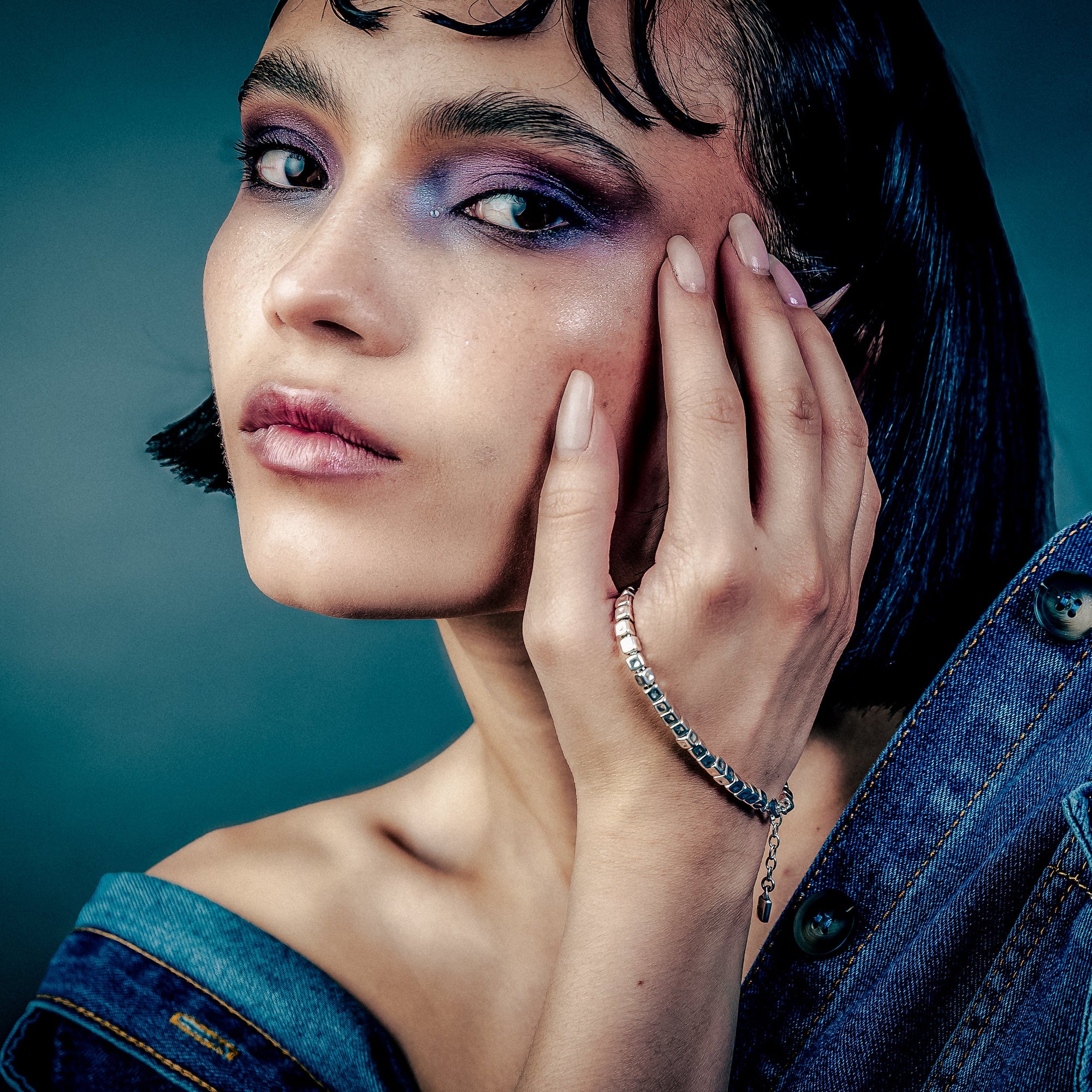 [full] Woman with dark hair and denim jacket wearing a sterling silver cube beads bracelet with matte finish and adjustable closure.