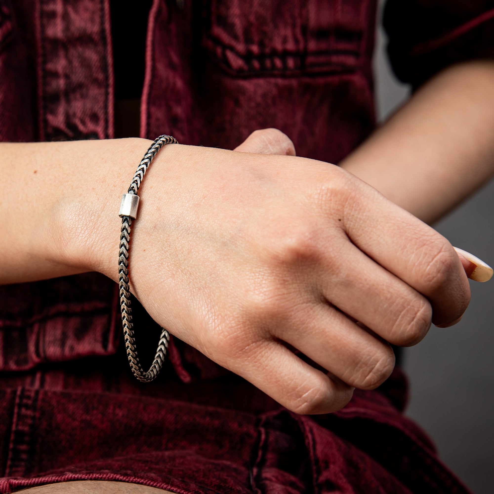 [full] Close-up of a person wearing a silver and ruthenium bracelet with a dark background