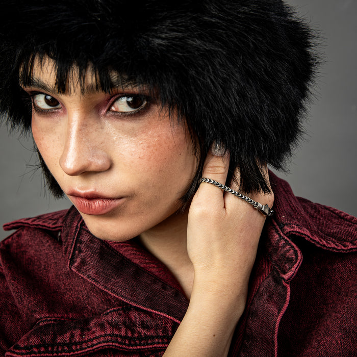 [full] Close-up of a person wearing a silver and ruthenium bracelet with a dark background