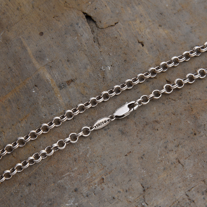 [full] - Close-up of sterling silver chain necklace with interlocking links and a fluid, modern design