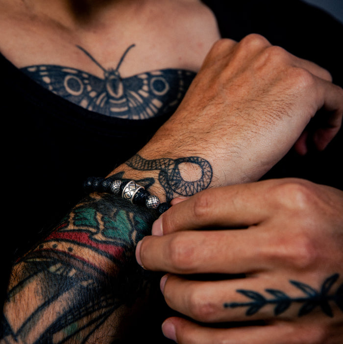 [full] - Close-up of man wearing black lava stone bead bracelet with sterling silver accents and matte finish.