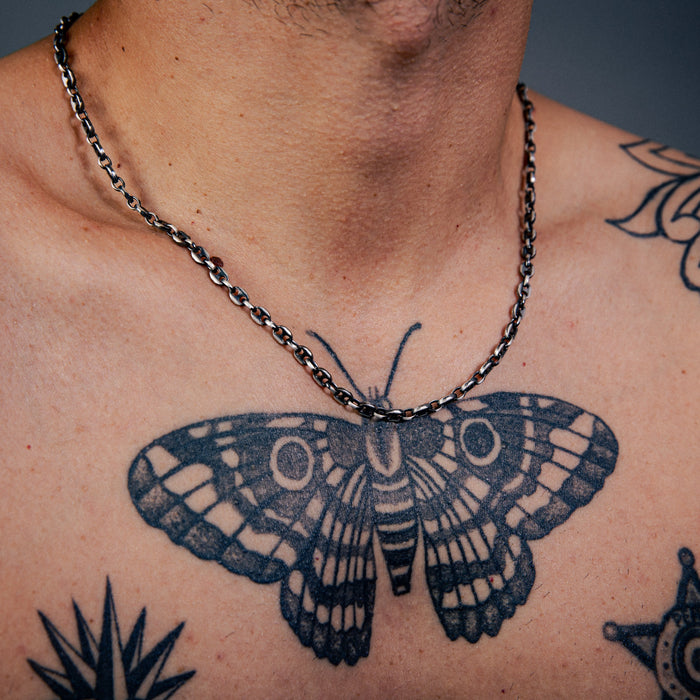 [full] Close-up of a person's chest with butterfly tattoo and chain sterling silver with ruthenium plating necklace