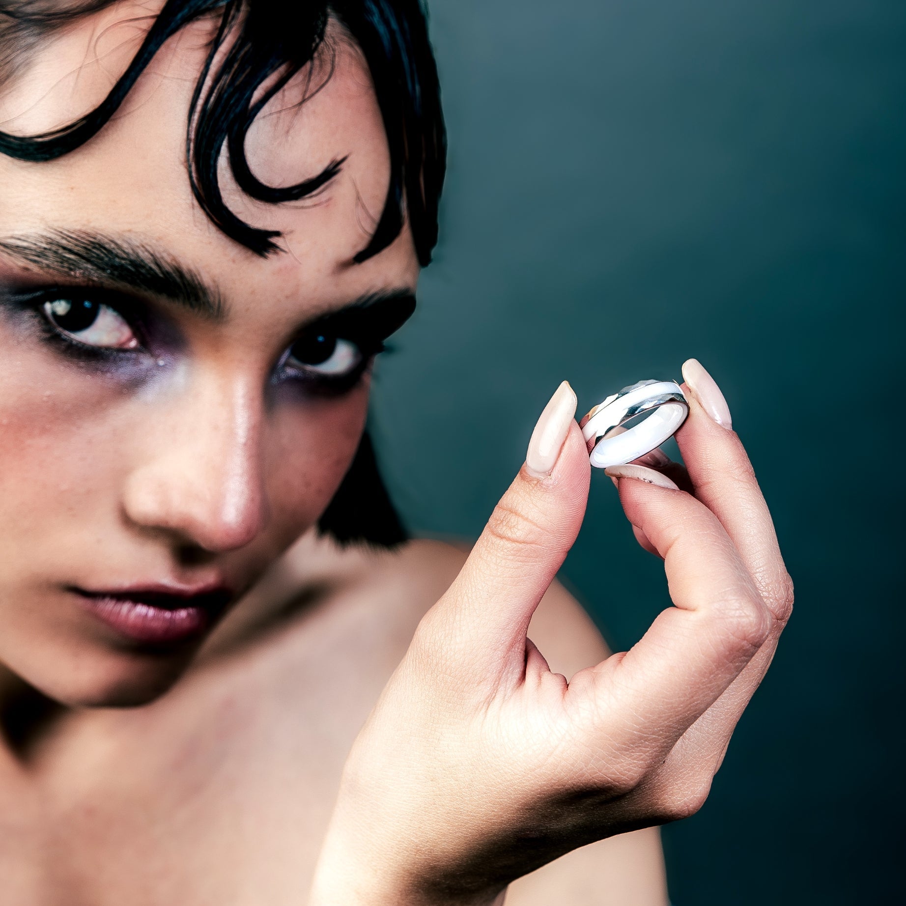 [full] Woman holding a white ceramic ring against a dark background