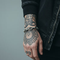 [full] Close-up of a person with tattoos wearing a sterling silver bracelet