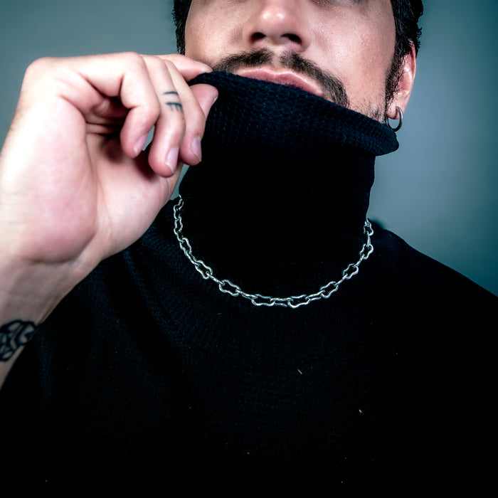 [full] - Man wearing a black turtleneck sweater with a chain silver necklace.