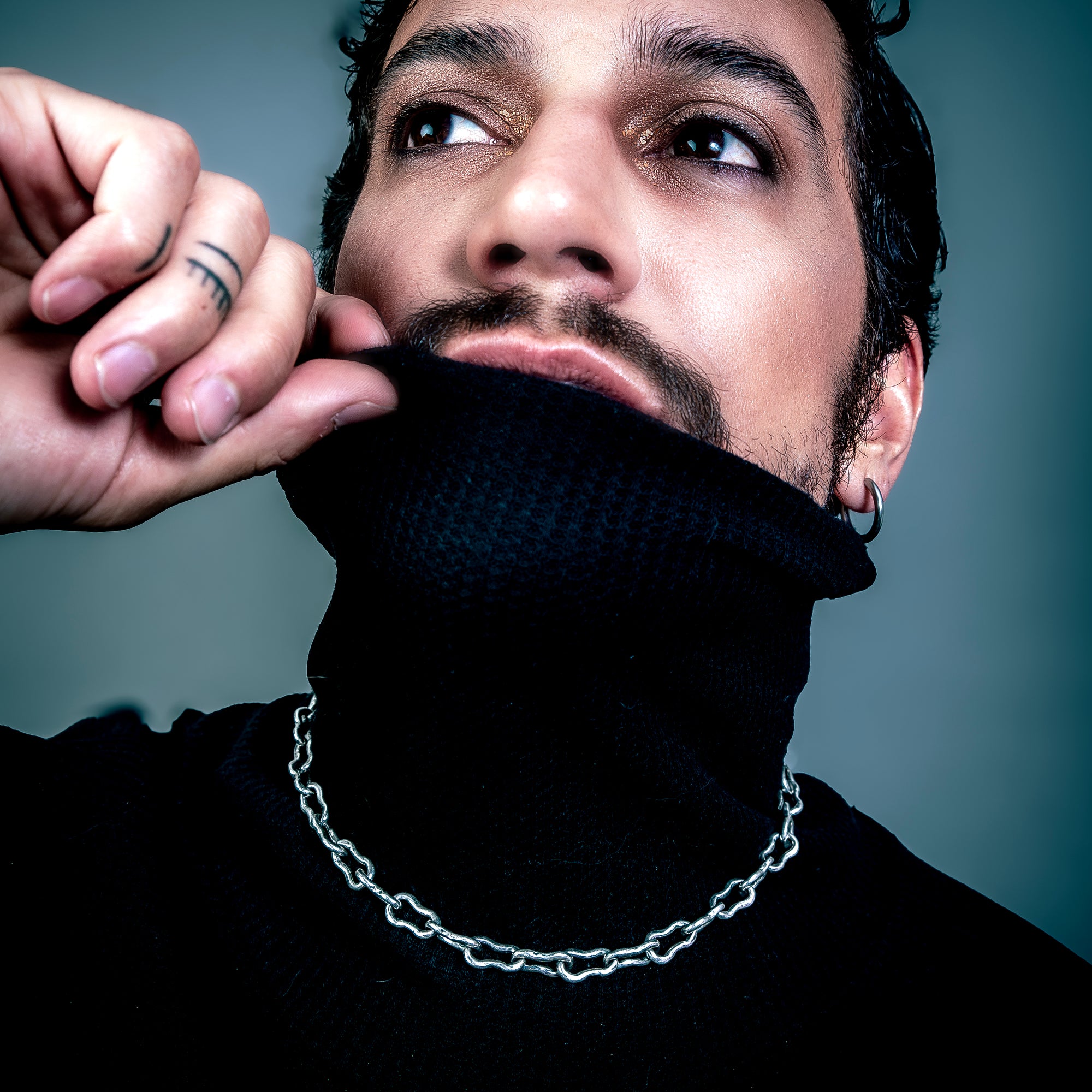 [full] - Man wearing a black turtleneck sweater with a chain silver necklace.