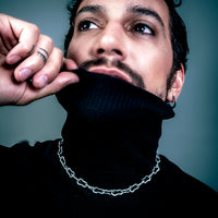 [full] - Man wearing a black turtleneck sweater with a chain silver necklace.