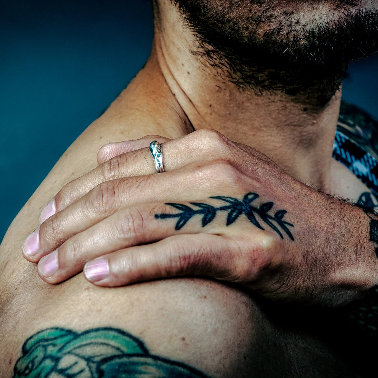 [full] - Man with tattoos with a silver ring against a blue background