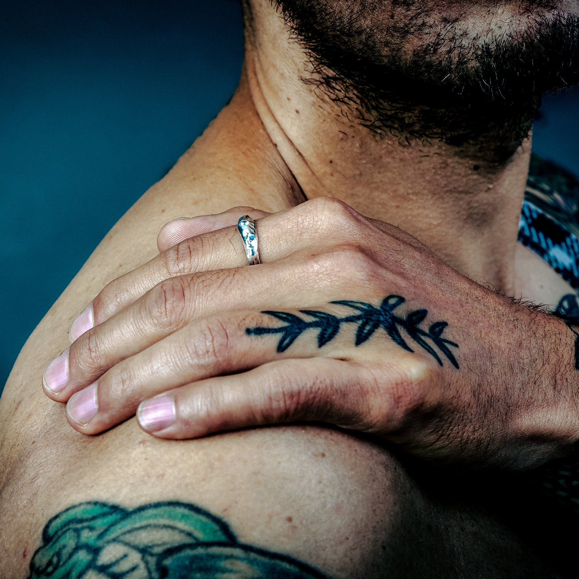 [full] - Man with tattoos with a silver ring against a blue background