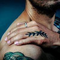 [full] - Man with tattoos with a silver ring against a blue background