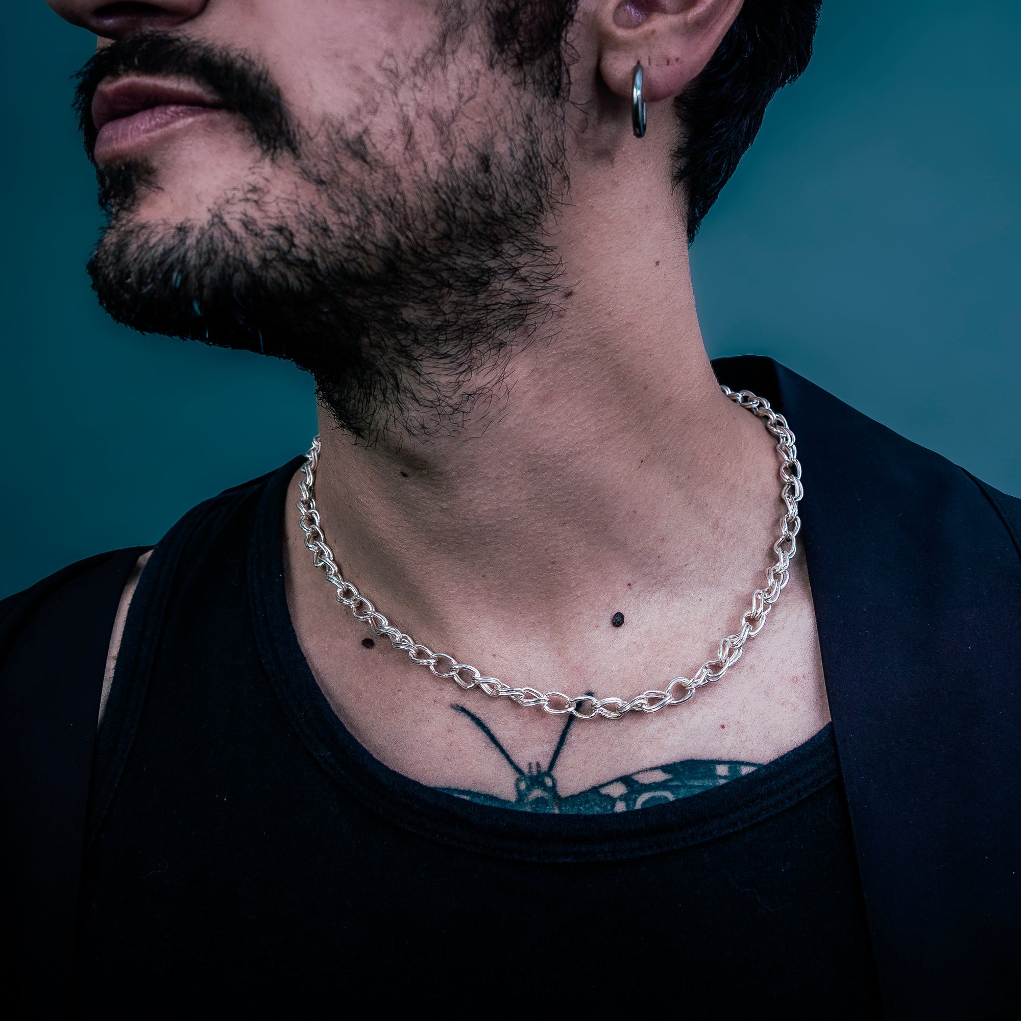 [full] Person wearing a chain necklace with a dark background