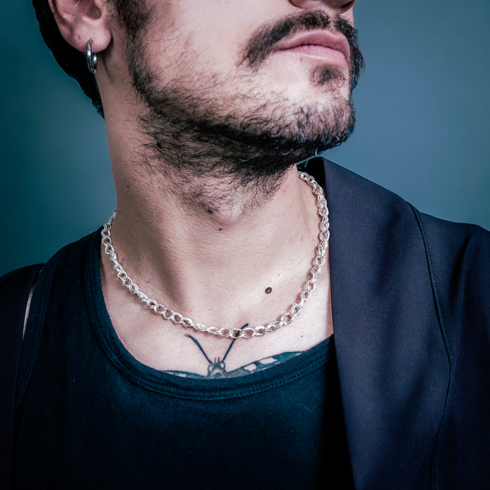 [full] Man wearing a silver chain necklace with a dark background