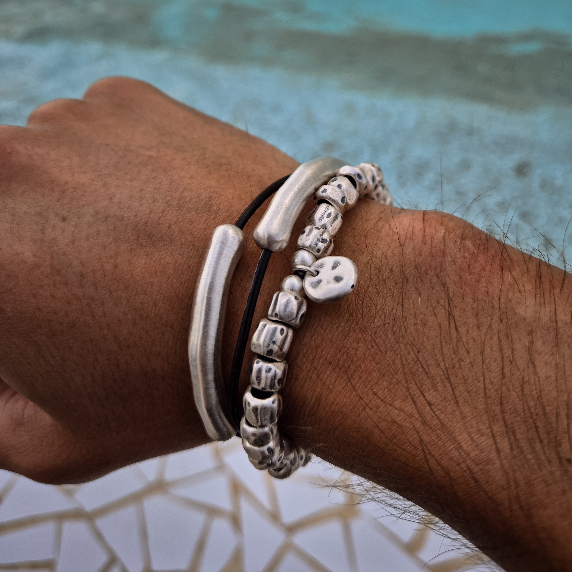 [full] Person wearing the Tempest Bracelet in 999 silver, featuring textured beads and polished accents, styled by the pool.