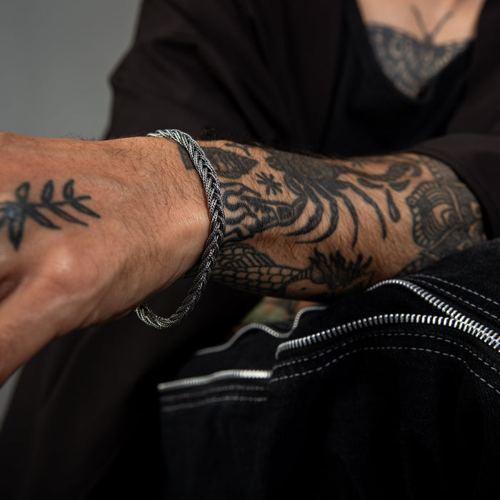 [full] - Close-up of a woven sterling silver bracelet with oxidised finish and intricate texture.