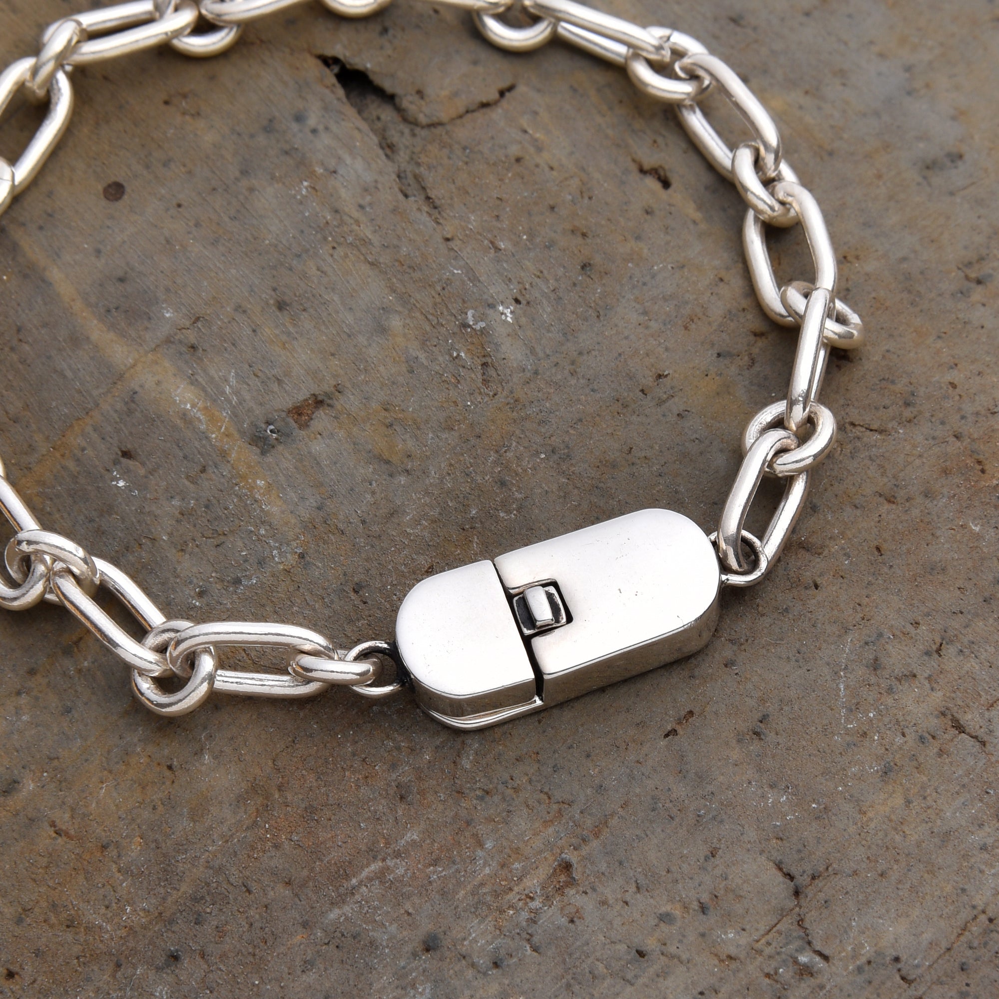 [full]-Silver chain bracelet with a clasp on a textured stone surface