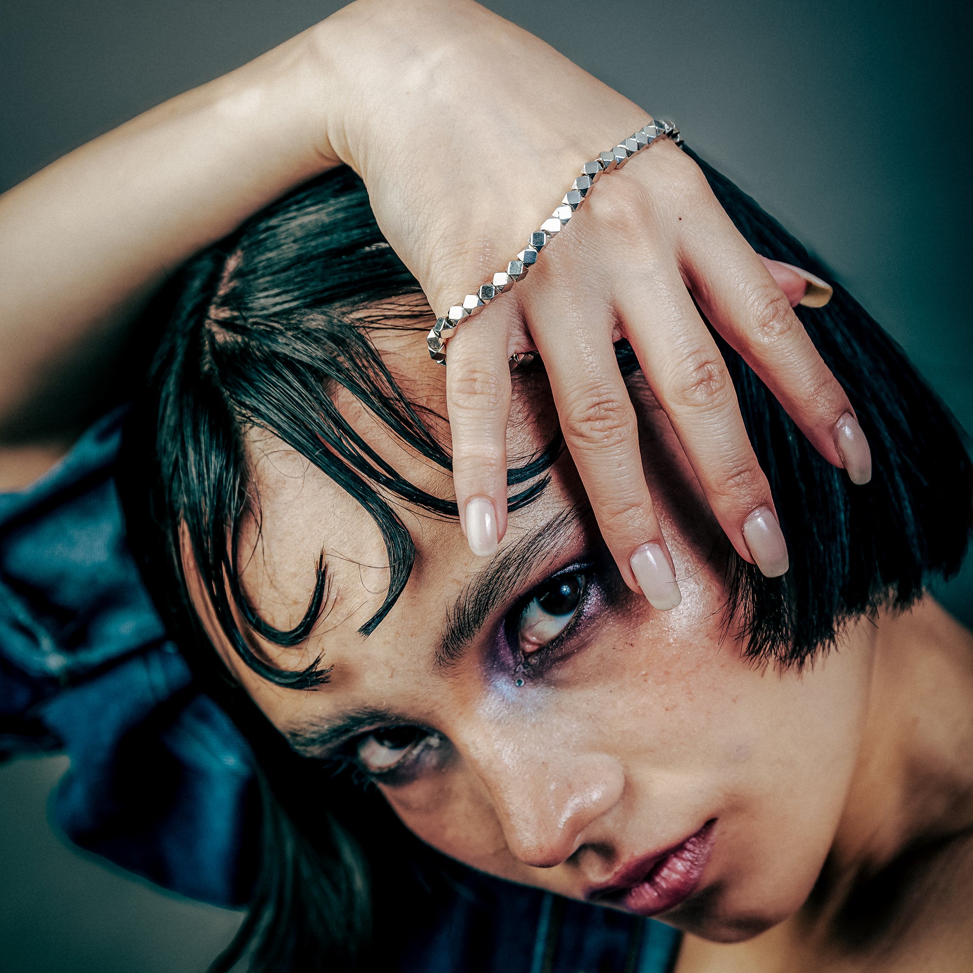 [full] - Woman with dark hair with faceted sterling silver beads bracelet with geometric design and polished finish.
