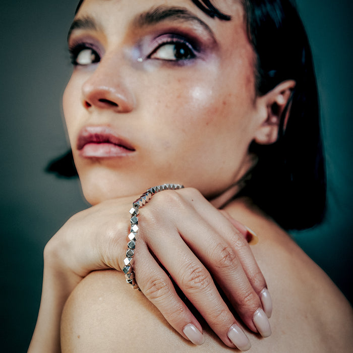 [full] - Woman with dark hair with faceted sterling silver beads bracelet with geometric design and polished finish.